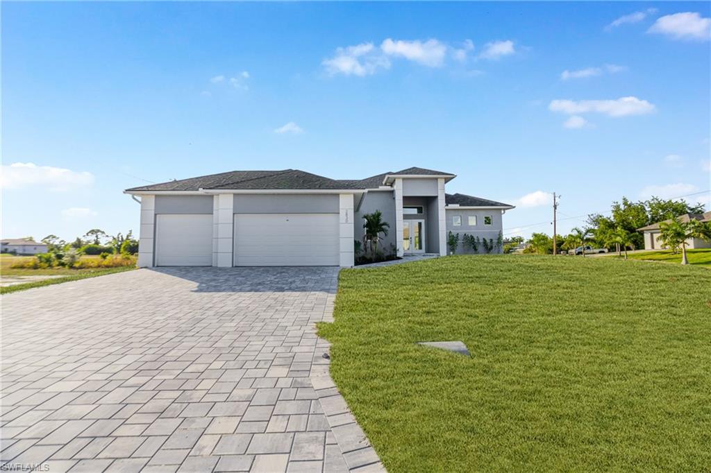 Image 2: Prairie-style house with a front yard, a garage, decorative driveway, and stucco siding