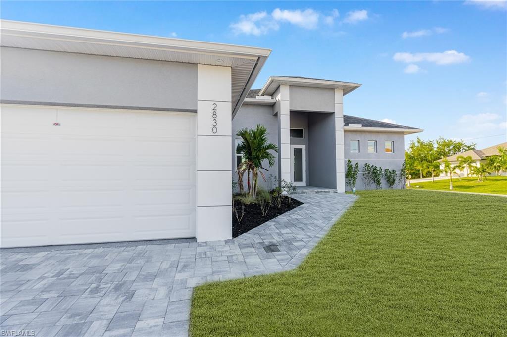 Image 4: Contemporary house with a front lawn, stucco siding, and a garage