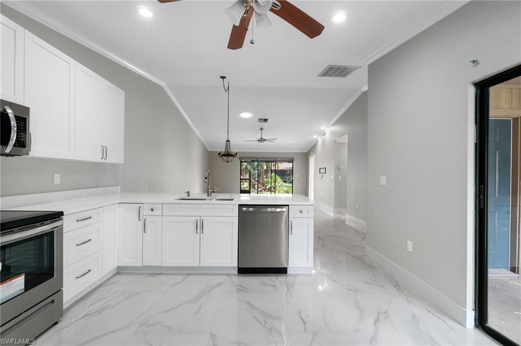 Image 4: Kitchen featuring appliances with stainless steel finishes, ceiling fan, crown molding, a peninsula, and white cabinets