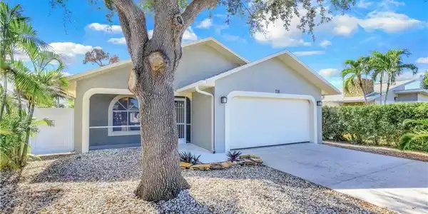 Image 2: View of front of house featuring an attached garage, stucco siding, and driveway