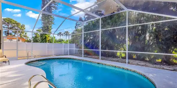 Image 4: View of pool with a fenced backyard, glass enclosure, a sunroom, and patio surround