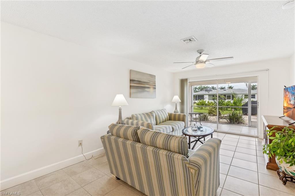 Image 4: Living area with light tile patterned flooring, a ceiling fan, and a textured ceiling
