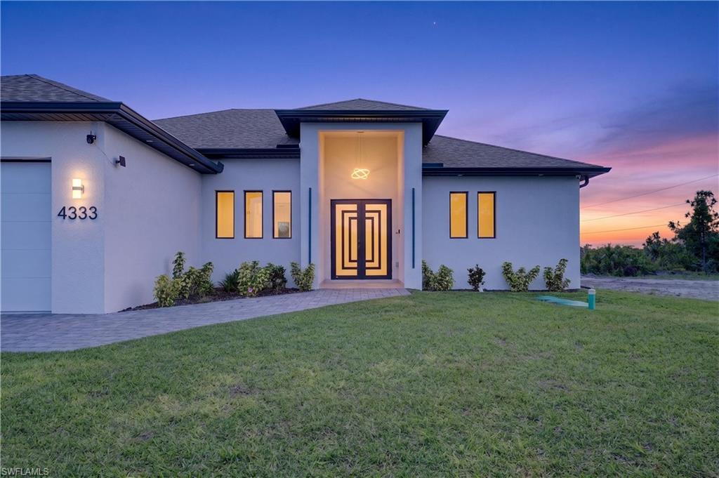 Image 3: Modern stucco exterior with a prominent entryway featuring a geometric door design