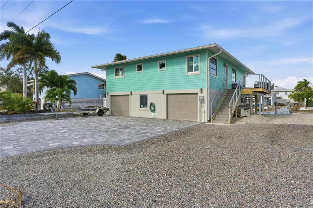 Image 3: Coastal inspired home with decorative driveway, stairway, and an attached garage - Virtually Edited Image