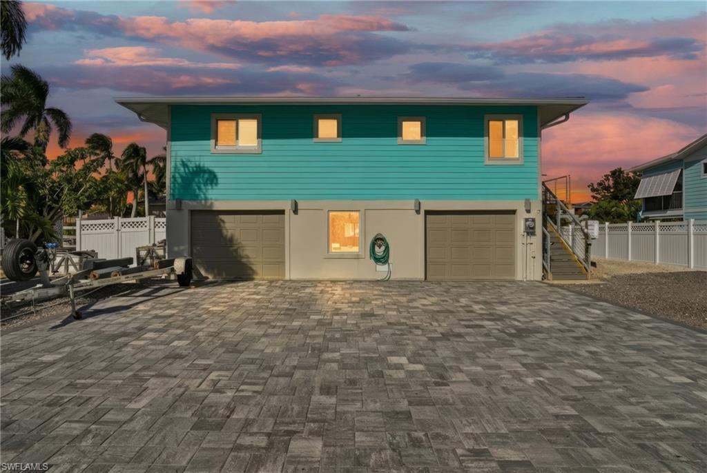 Image 4: Coastal home featuring decorative driveway, stairway, and an attached garage - Virtually Edited Image