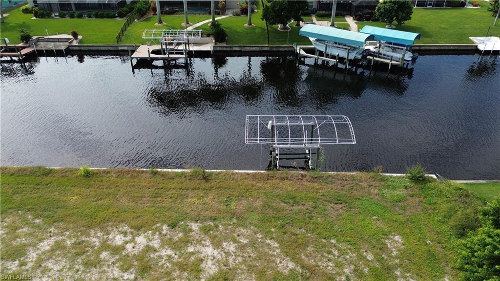 Image 4: Dock with boat lift, a water view, and a lawn