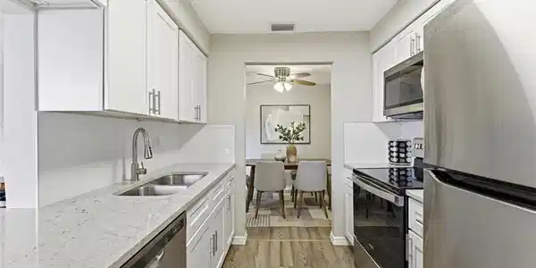 Image 3: Kitchen featuring stainless steel appliances, backsplash, light stone countertops, and white cabinets