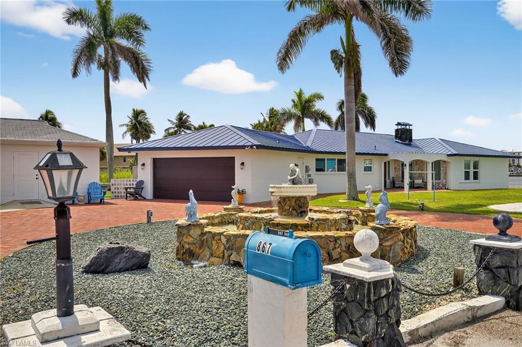 Image 2: Ranch-style home featuring an attached garage, driveway, a metal roof, stucco siding, and a chimney