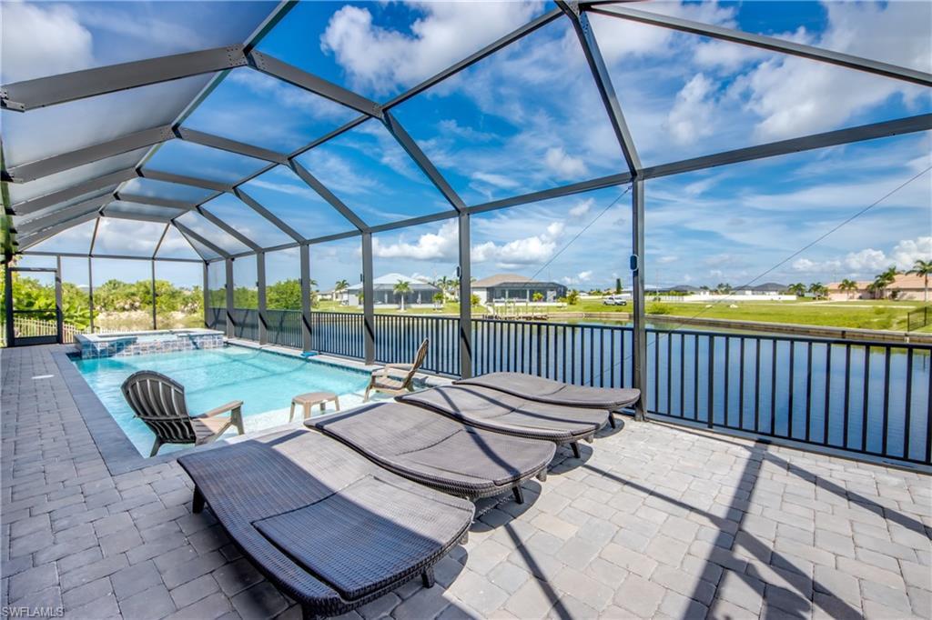 Image 2: View of swimming pool with a pool with connected hot tub, a patio, a residential view, a water view, and glass enclosure