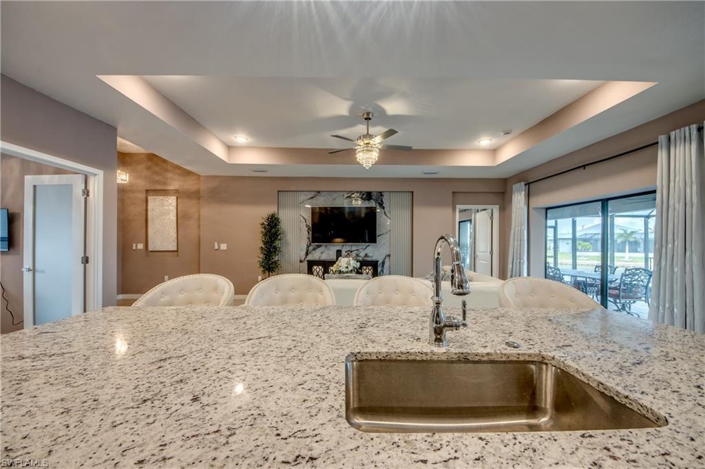 Image 4: Kitchen with appliances with stainless steel finishes, a kitchen bar, an island with sink, light stone counters, and recessed lighting