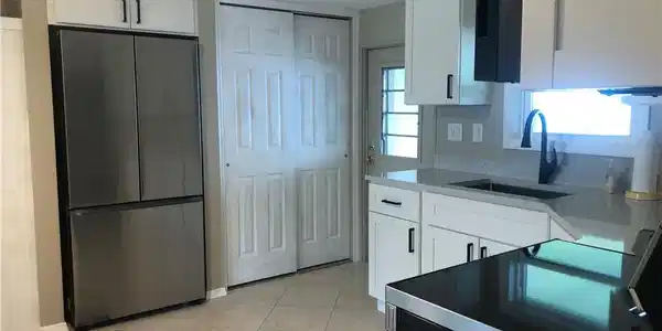 Image 3: Kitchen featuring stainless steel appliances refrigerator, sink, and white cabinets