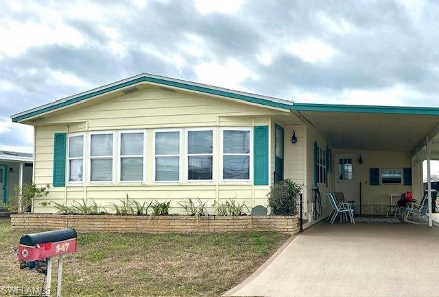 Image 1: Manufactured / mobile home featuring a carport, a front lawn, driveway, and a patio area