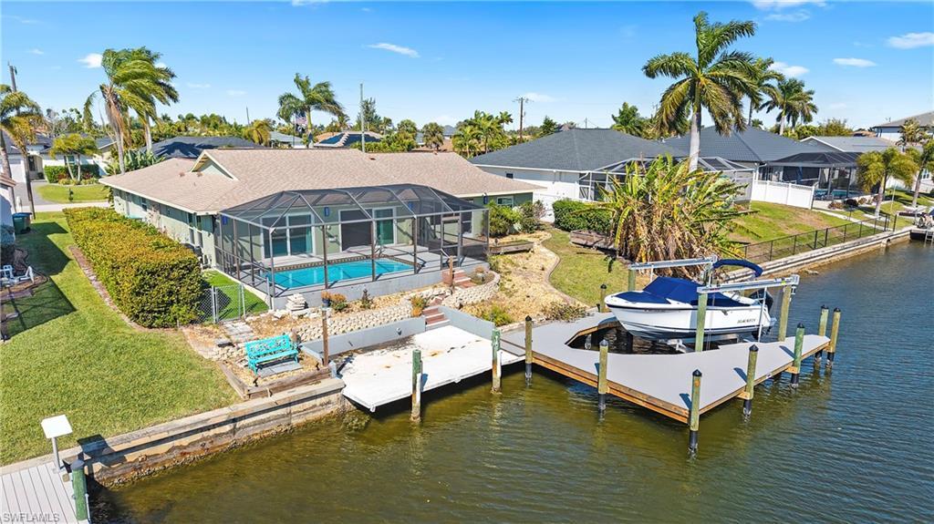 Image 1: Dock with an outdoor pool, a lanai, boat lift, a water view, and a sunroom