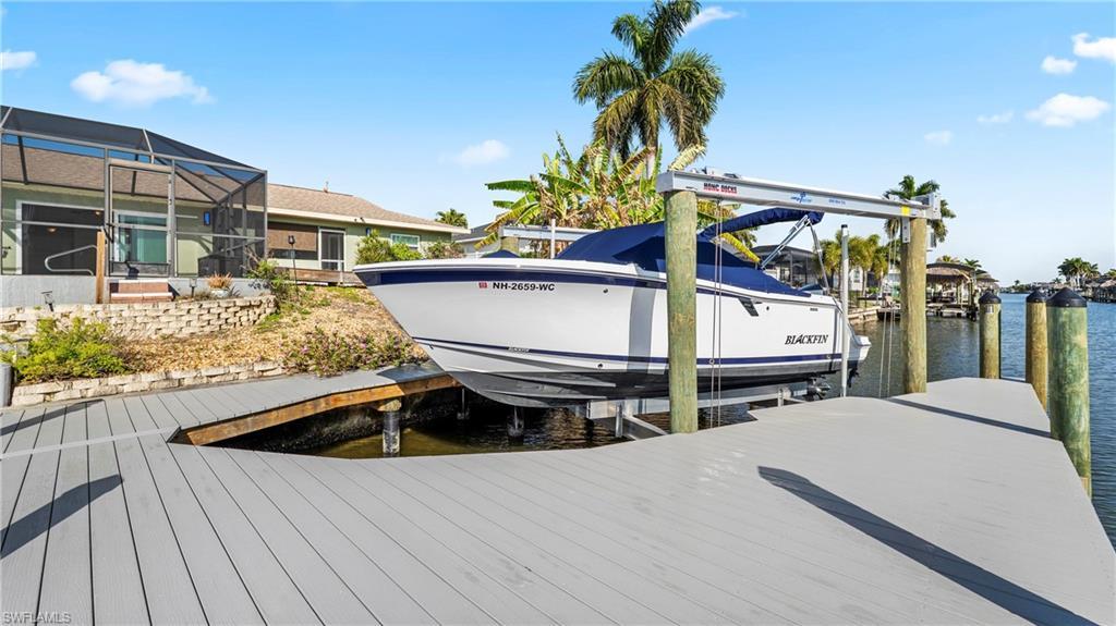 Image 3: Dock with boat lift, a water view, glass enclosure, and a sunroom