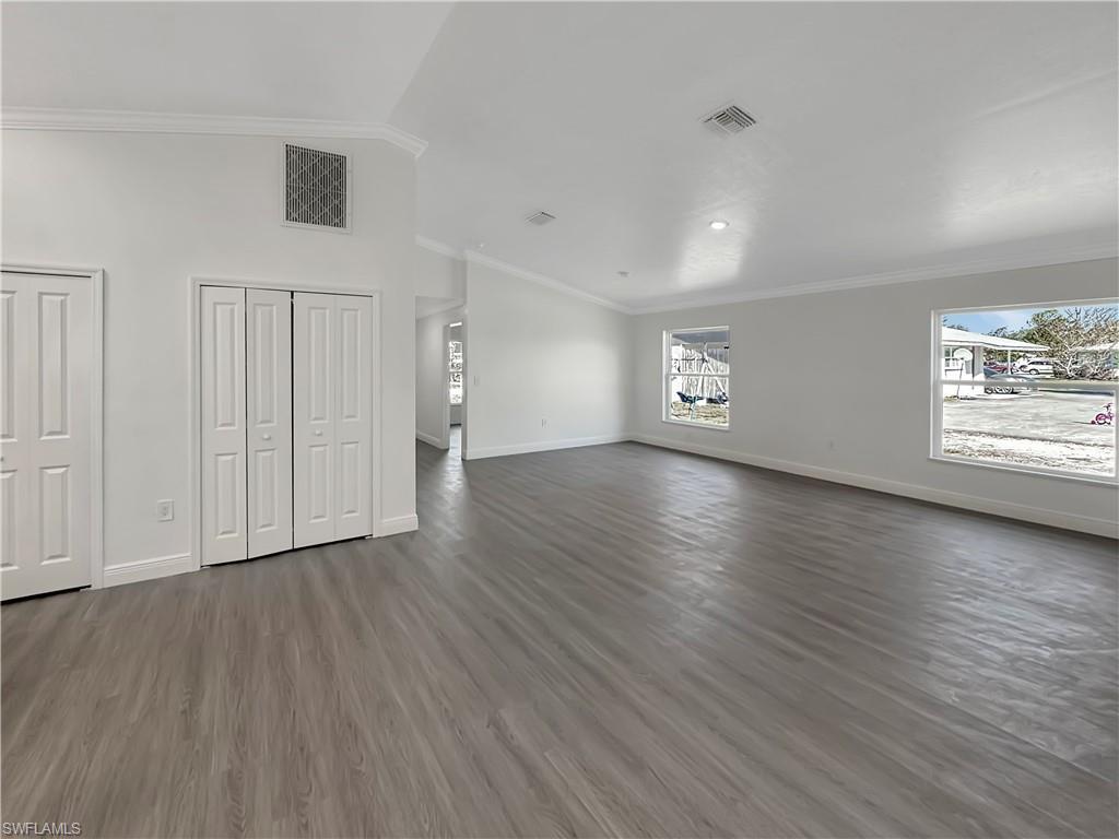 Image 2: Unfurnished living room with vaulted ceiling, ornamental molding, and dark wood-style floors