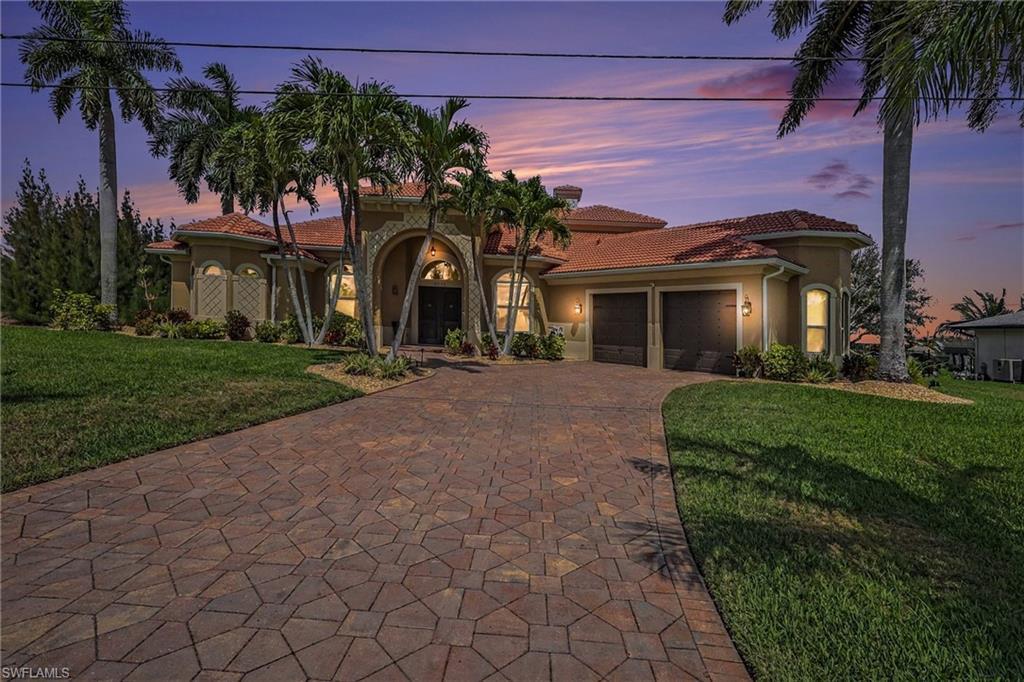 Image 3: Mediterranean / spanish-style house with a yard, stucco siding, an attached garage, a tiled roof, and decorative driveway