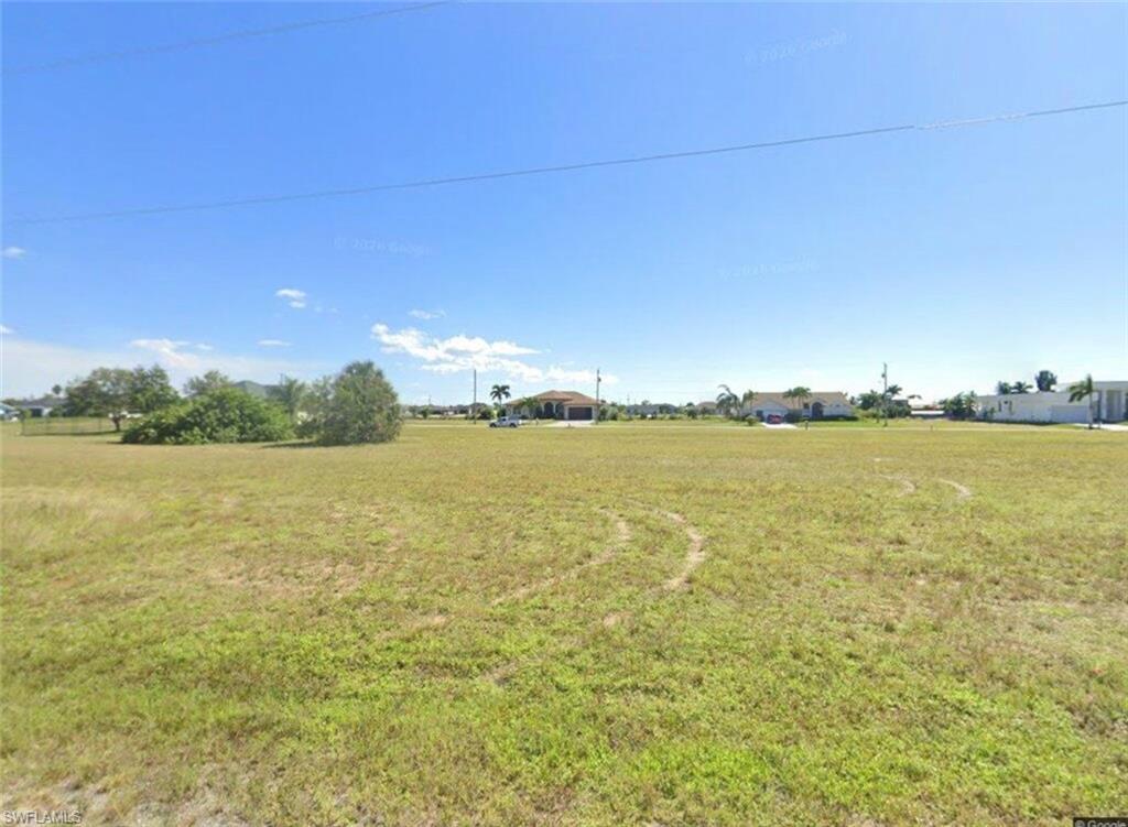 Image 1: Expansive undeveloped lot featuring natural grass and scattered low-lying vegetation