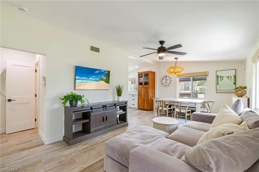 Image 1: Open concept living area featuring wood-finish flooring, a ceiling fan with integrated lighting, recessed lighting, and a built-in wood-finish cabinet