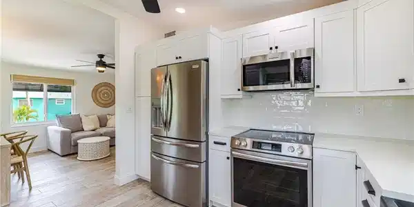 Image 3: Contemporary kitchen featuring stainless steel appliances, white shaker cabinetry, white subway tile backsplash, and light-toned countertops