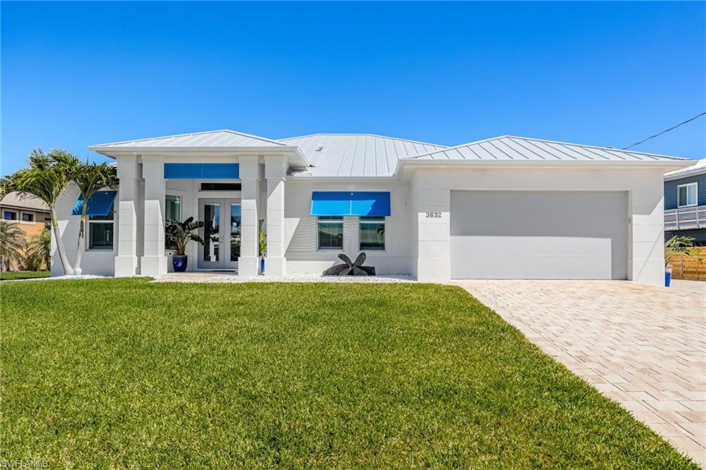 Image 4: View of front of house with a front yard, a standing seam roof, stucco siding, decorative driveway, and metal roof