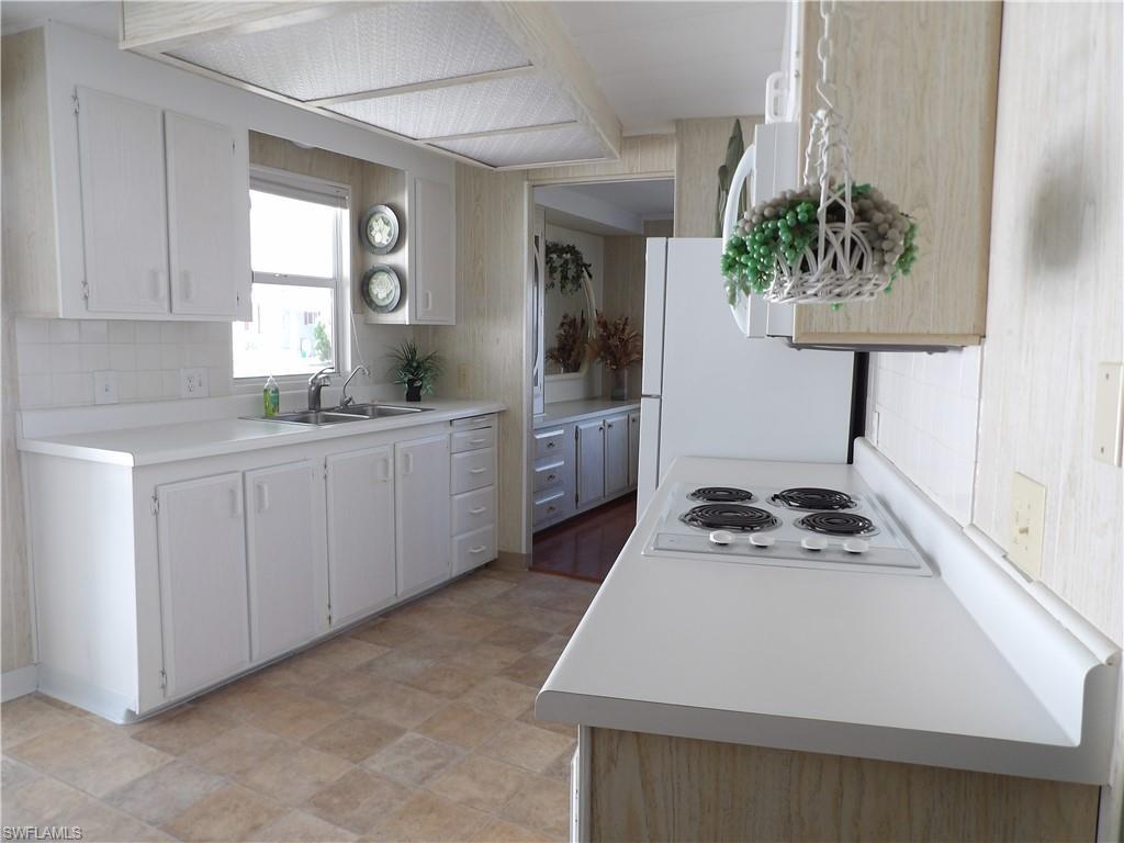 Image 4: Kitchen with light countertops, tasteful backsplash, freestanding refrigerator, and white cabinets
