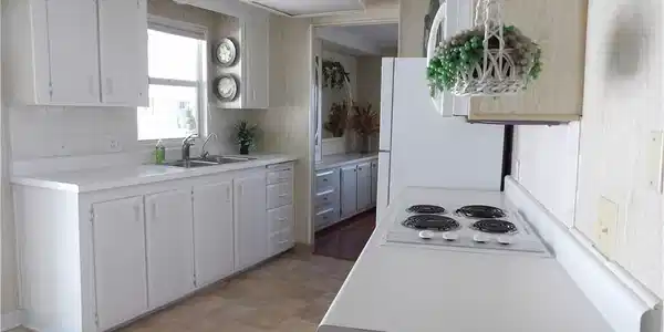 Image 4: Kitchen with light countertops, tasteful backsplash, freestanding refrigerator, and white cabinets