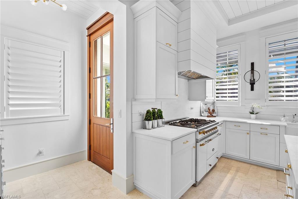 Image 4: Kitchen featuring white cabinets, custom range hood, and white gas stovetop
