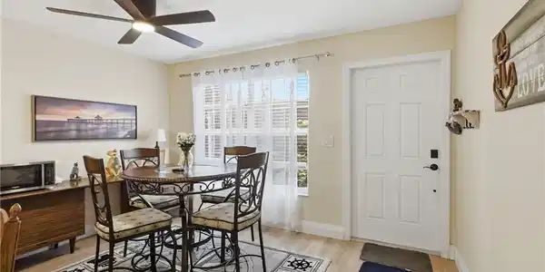 Image 2: Dining area featuring wood-finish flooring, a contemporary ceiling fan with integrated lighting, and a white paneled entry door