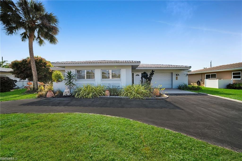 Image 1: Single-story residence featuring a paved driveway, attached garage, and mature landscaping