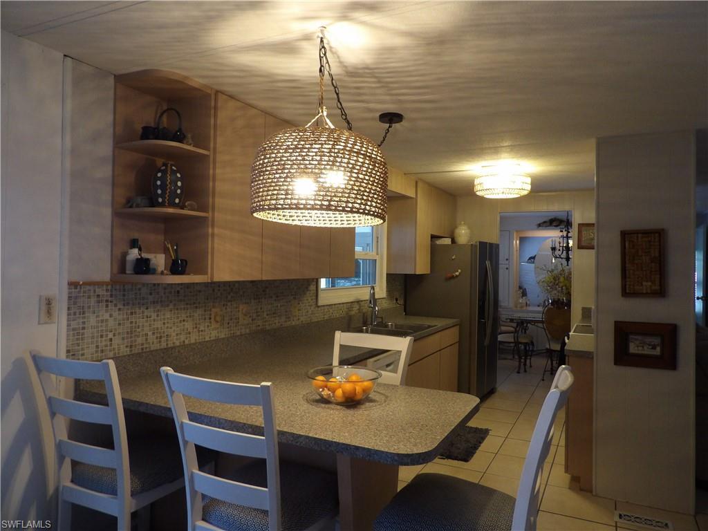 Image 3: Kitchen featuring a kitchen breakfast bar, a peninsula, decorative light fixtures, open shelves, and light tile patterned flooring
