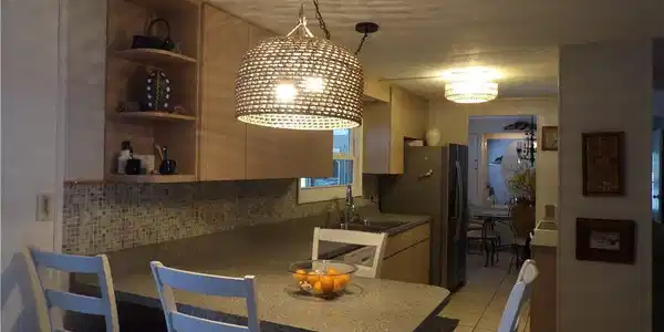 Image 3: Kitchen featuring a kitchen breakfast bar, a peninsula, decorative light fixtures, open shelves, and light tile patterned flooring