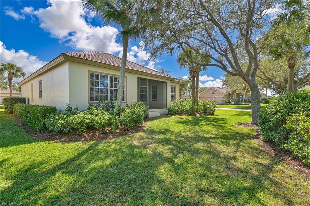 Image 3: Rear view of property featuring a lawn, a sunroom, stucco siding, and a tiled roof