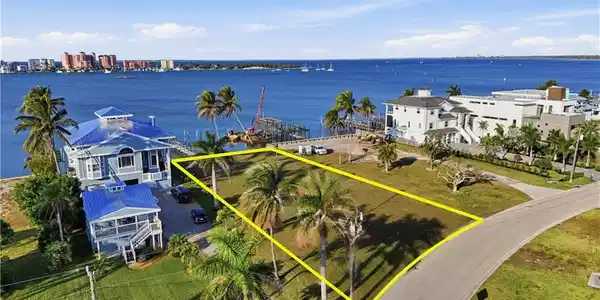 Image 2: Aerial view of property and surrounding area with a large body of water and property parcel outlinedchange color of water into natural dark blue canal water