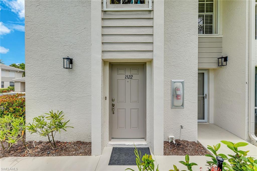 Image 4: Entryway featuring a painted door with a numeric address placard and black exterior lighting fixtures