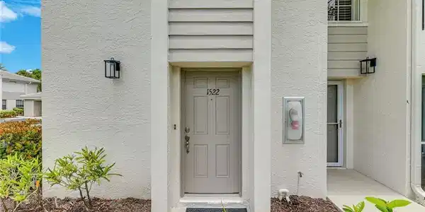 Image 4: Entryway featuring a painted door with a numeric address placard and black exterior lighting fixtures