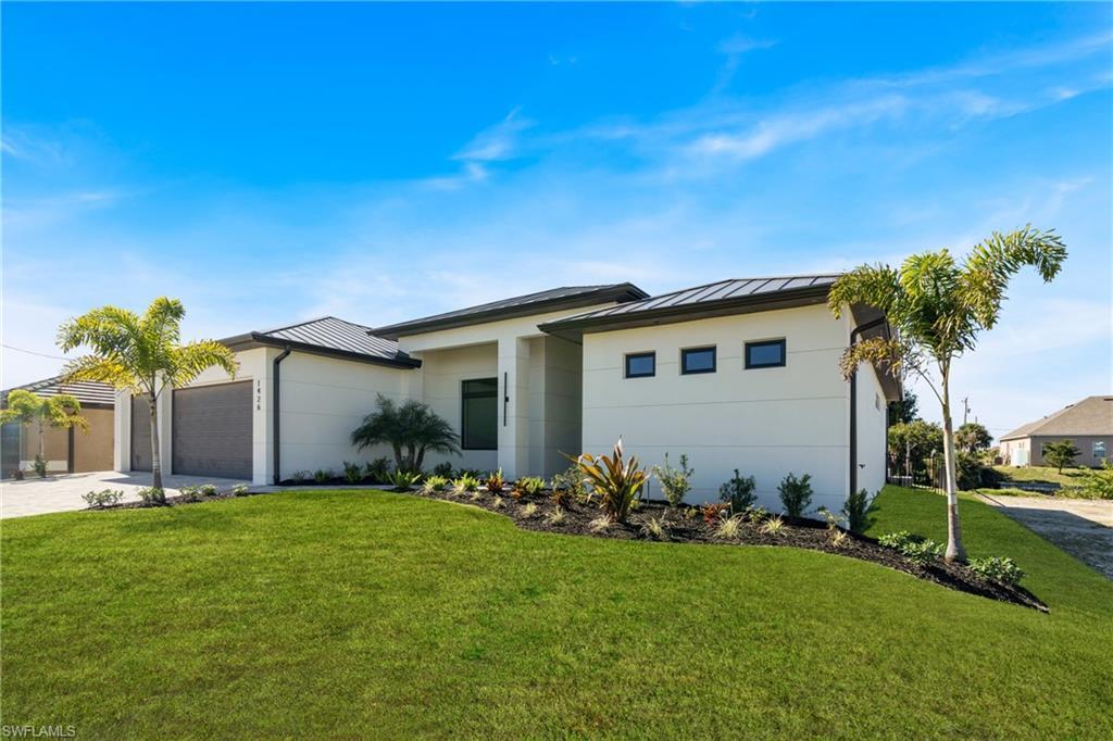 Image 3: View of front of home featuring a standing seam roof, a metal roof, a front yard, driveway, and an attached garage