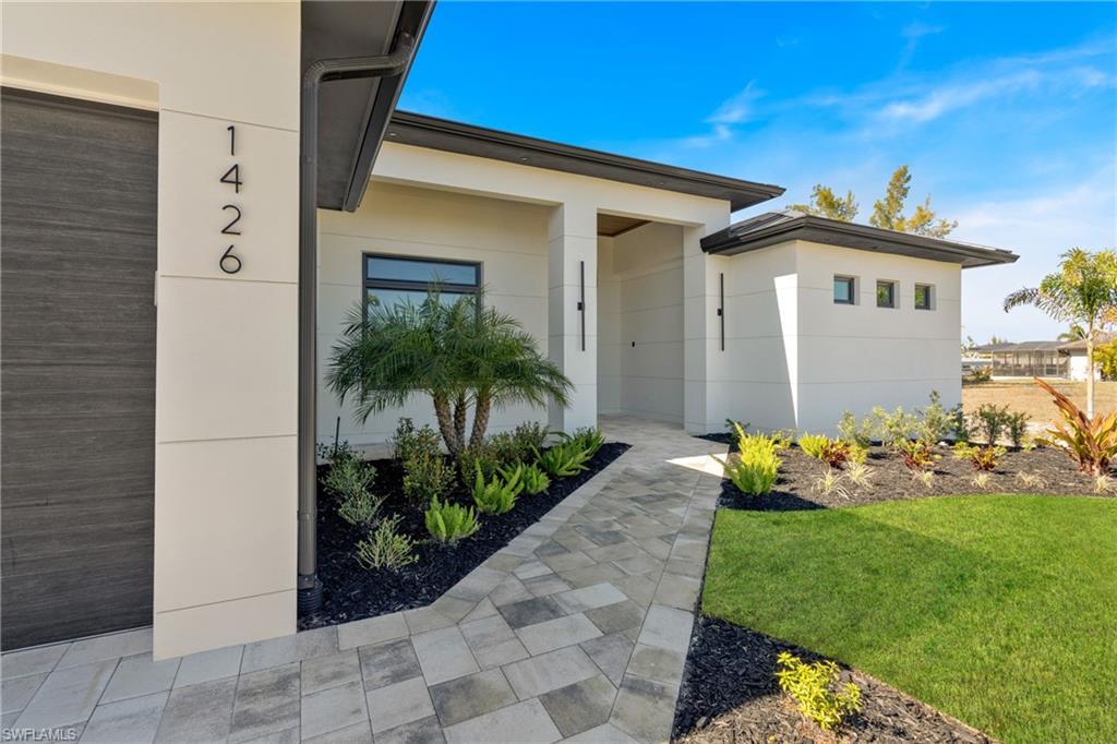 Image 4: Doorway to property with a lawn and stucco siding