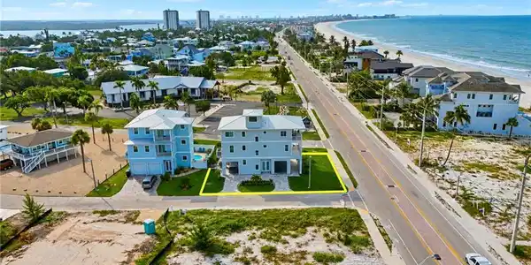 Image 4: Coastal-style residence featuring multiple balconies, a ground-level garage, and a manicured lawn - Virtually Edited Image