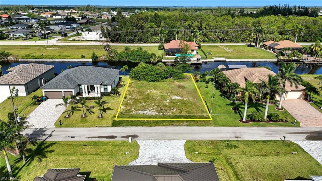 Image 3: Aerial view of residential area featuring a large body of water and property parcel outlined