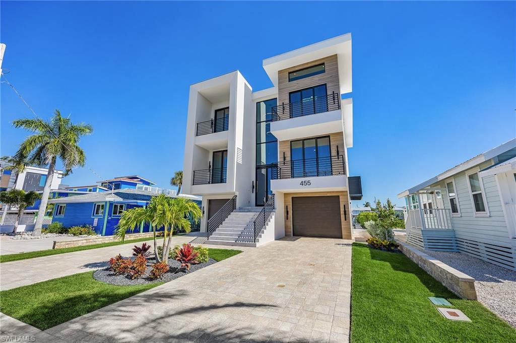 Image 3: Modern home with decorative driveway, stucco siding, an attached garage, a balcony, and a front lawn - Virtually Edited Image