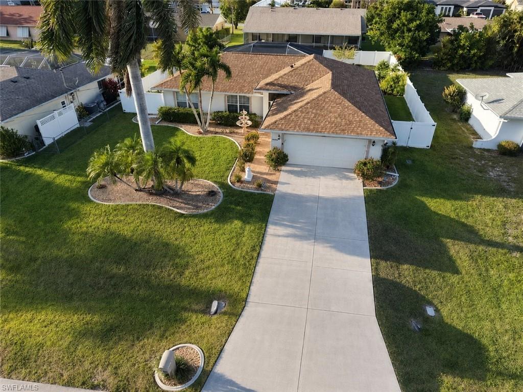 Image 1: Single-story residence featuring a shingled roof, two-car garage, concrete driveway, and white perimeter fencing