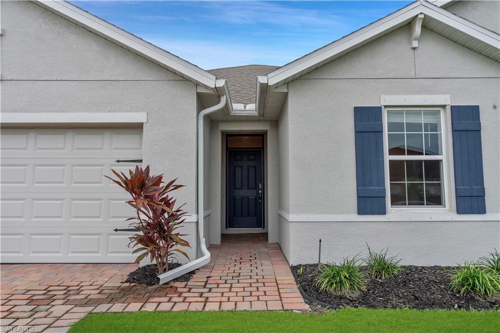 Image 3: View of front of home with stucco siding, a garage, and roof with shingles