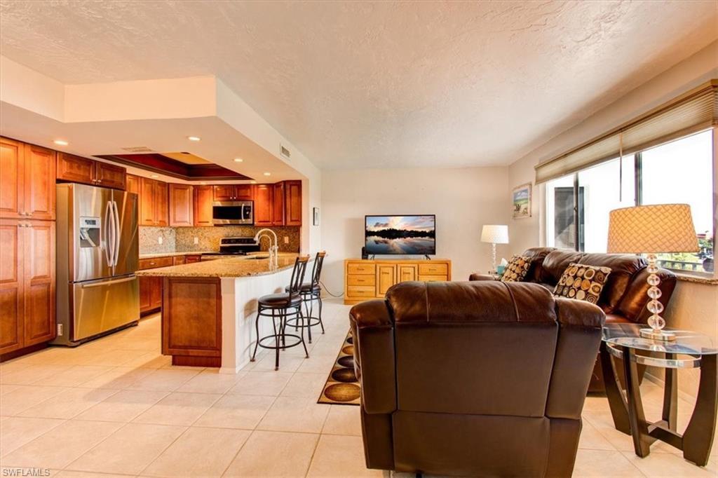 Image 3: Tiled living room with a textured ceiling, a tray ceiling, and sink
