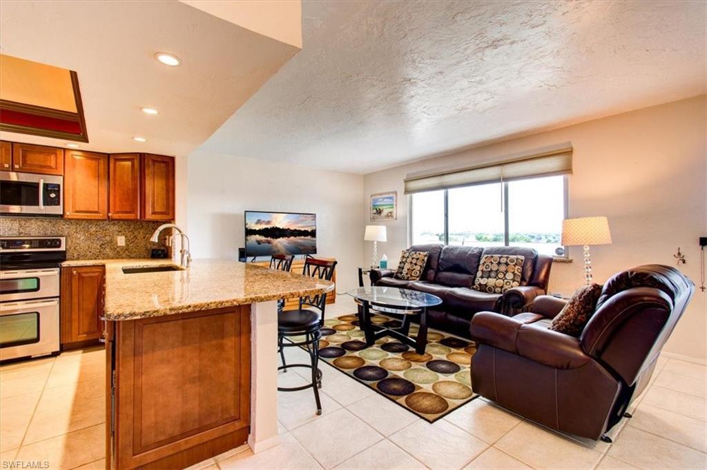 Image 4: Kitchen featuring light tile patterned floors, sink, kitchen peninsula, stainless steel appliances, and a kitchen bar