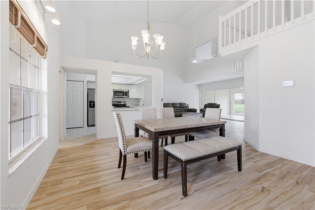 Image 3: Vaulted ceilings accent this open-concept dining area featuring wood-finish flooring
