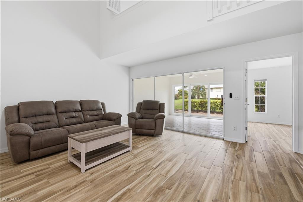 Image 4: Spacious living area featuring wood-finish flooring, soaring ceilings, and white walls