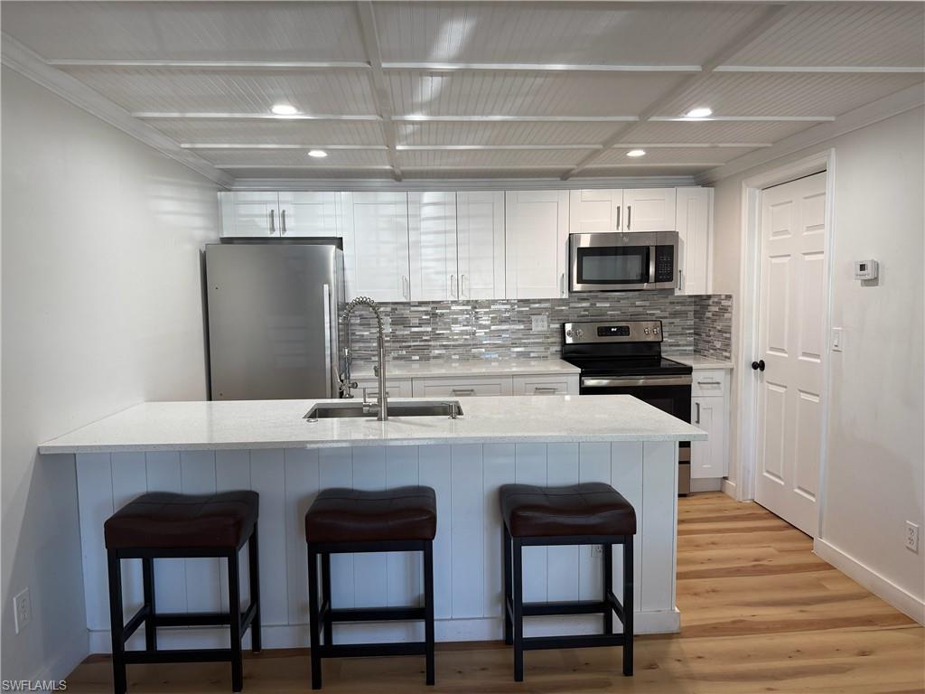 Image 4: Kitchen with  breakfast bar, stainless steel appliances, white cabinets, and light stone countertops