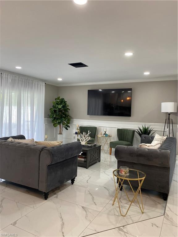 Image 1: Living area with a wainscoted wall, crown molding, marble tiled floors, a decorative wall, and recessed lighting