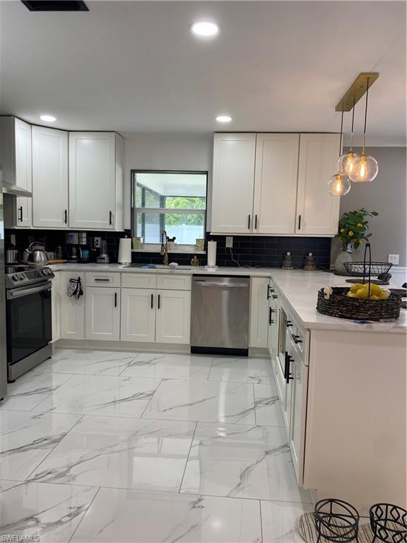 Image 3: Kitchen with white cabinets, dishwashing machine, light marble finish floors, range, and recessed lighting