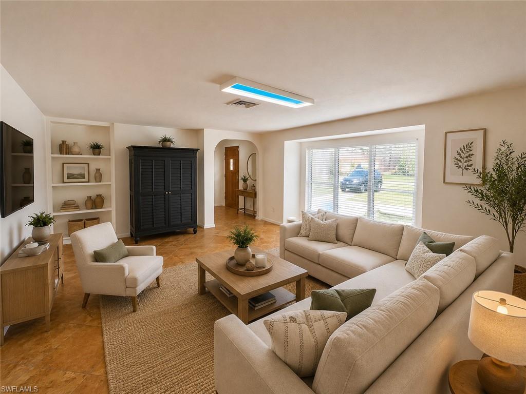 Image 1: Spacious living area featuring large front windows, built-in shelving, arched doorways, and wood-finish flooring